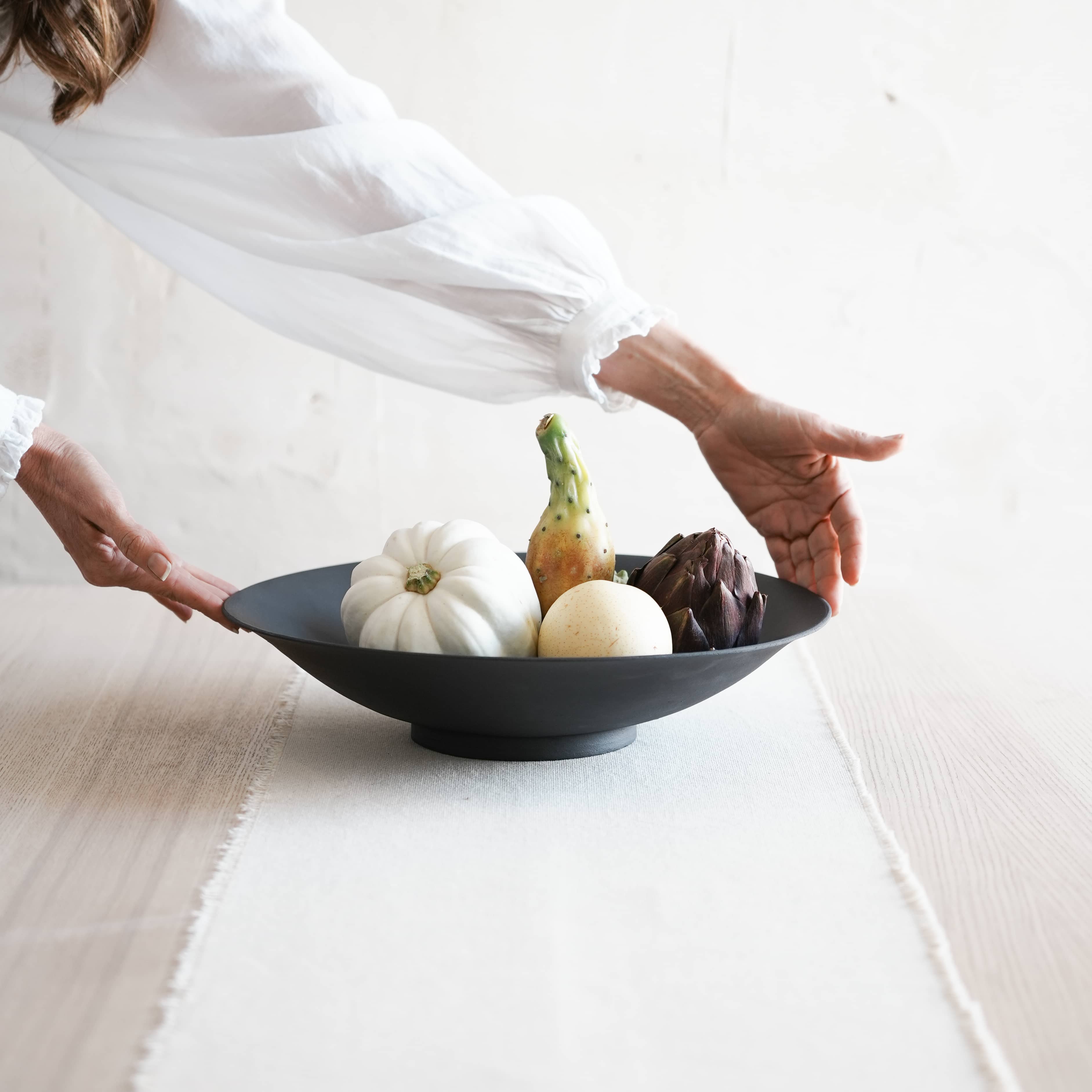 large black decorative bowl photographed at an angle and styled with fruits
