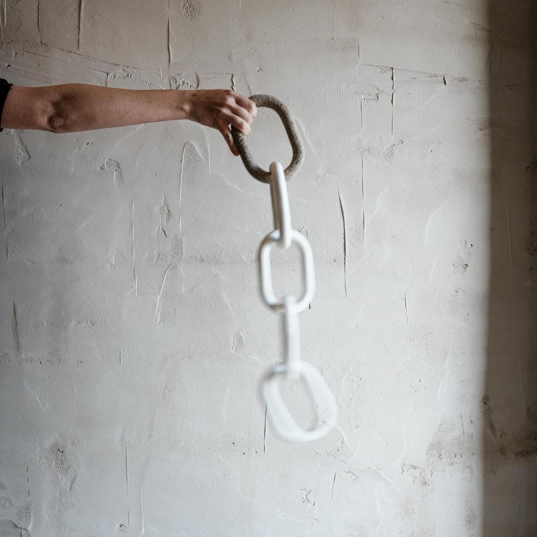 Handcrafted porcelain chain sculpture held by hand in ceramic studio
