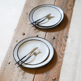 a set table of medium plates over large plates, each with a fork and a knife