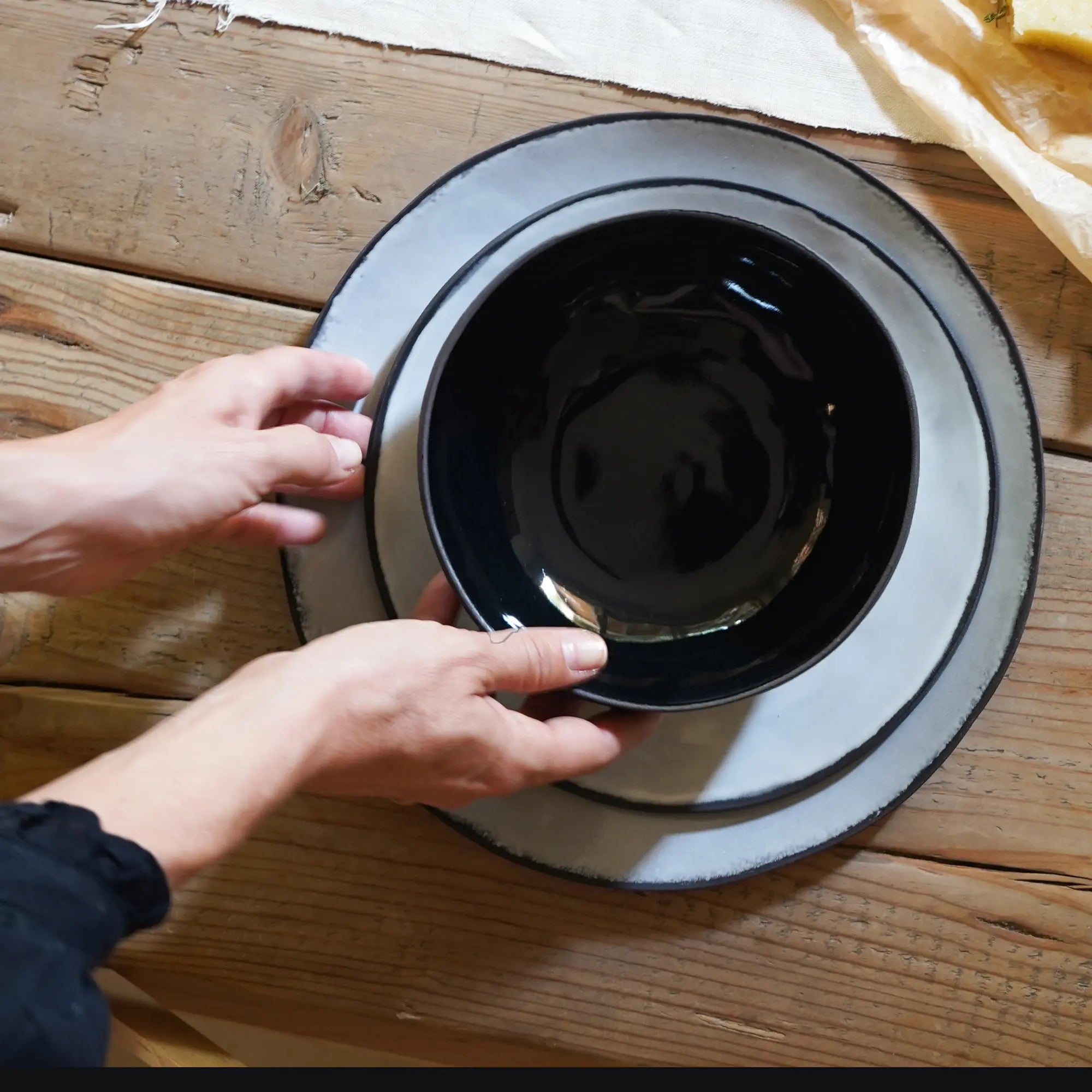 a plates setting of one black bowl, one salad plate and one dinner plate