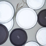 aerial photograph of many farmhouse plates, some bigger, some smaller, some upside down to show the black base