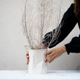 hands place white crumpled vase with white flowers