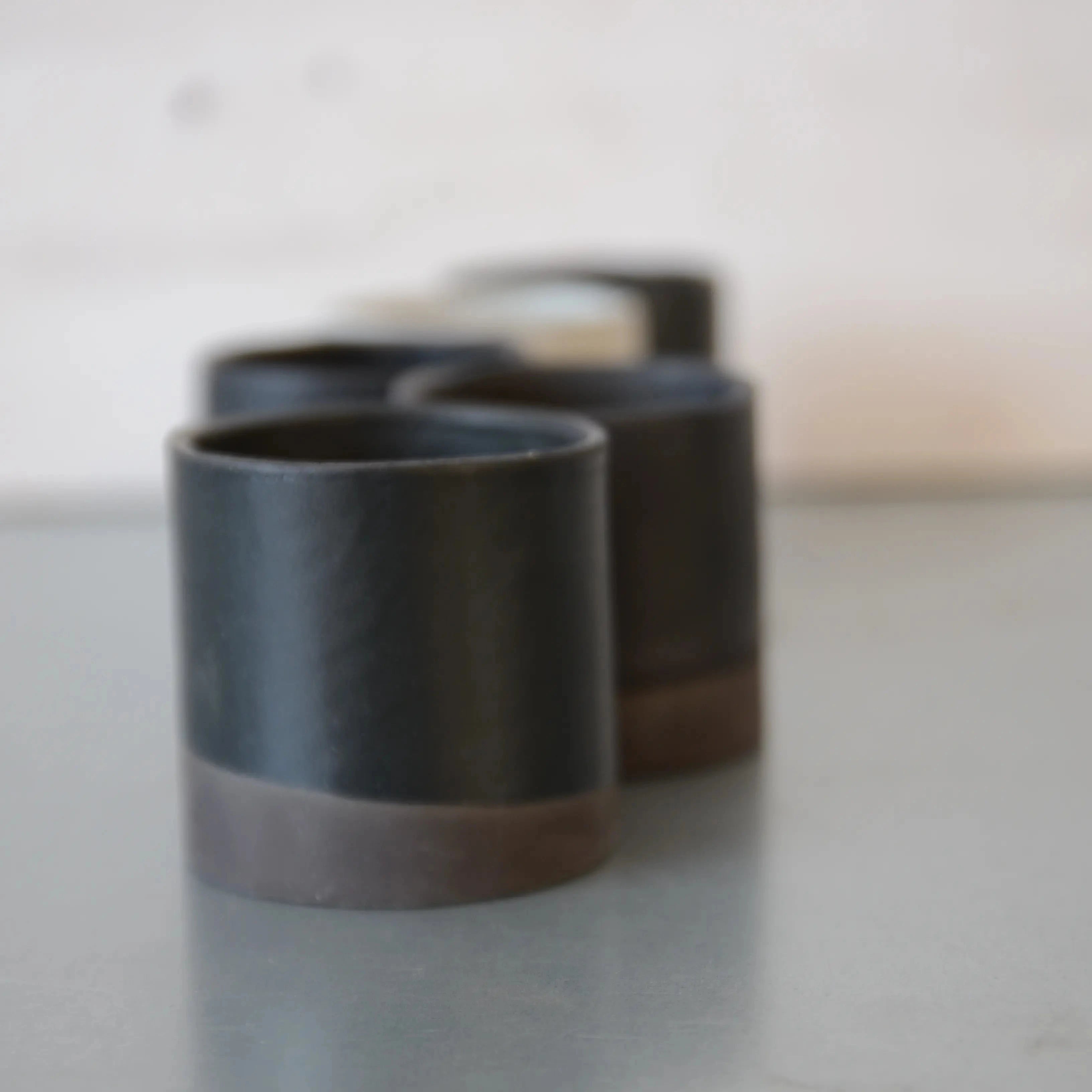 line of black double espresso cups. some are glazed black, some white