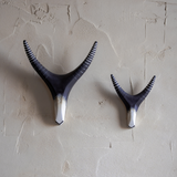 Two pairs of handpainted antlers mounted on a textured wall.