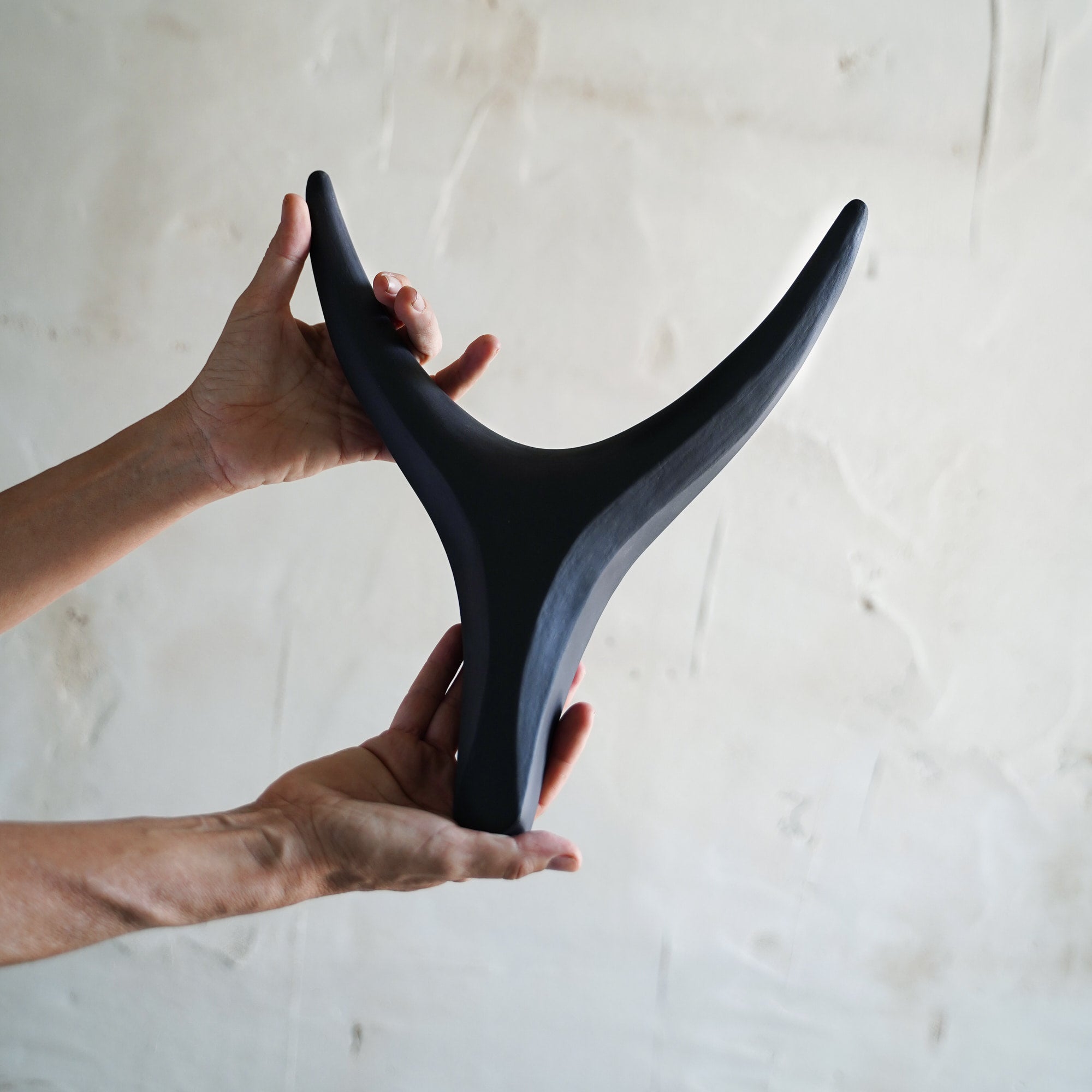 Person holding a black ceramic antler against a light background