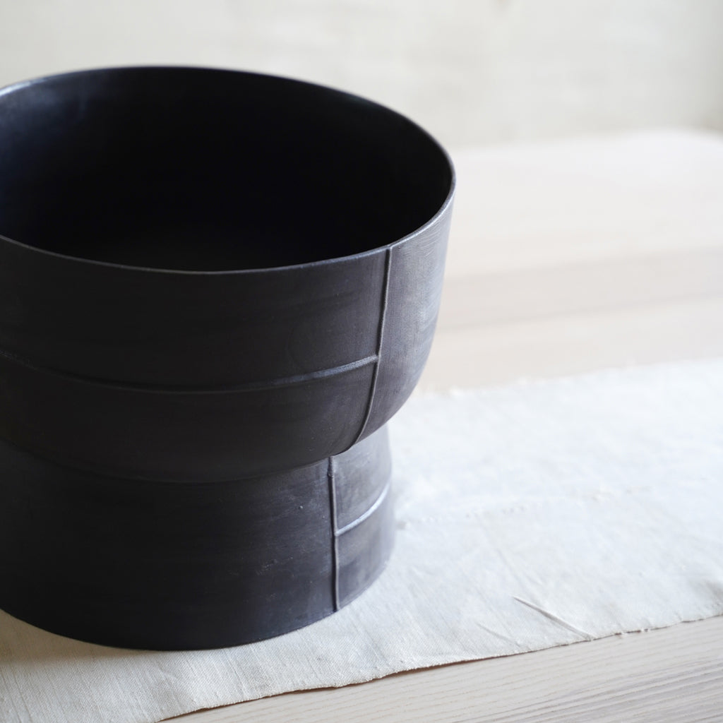 Minimalist black ceramic bowl on pedestal, modern table centerpiece