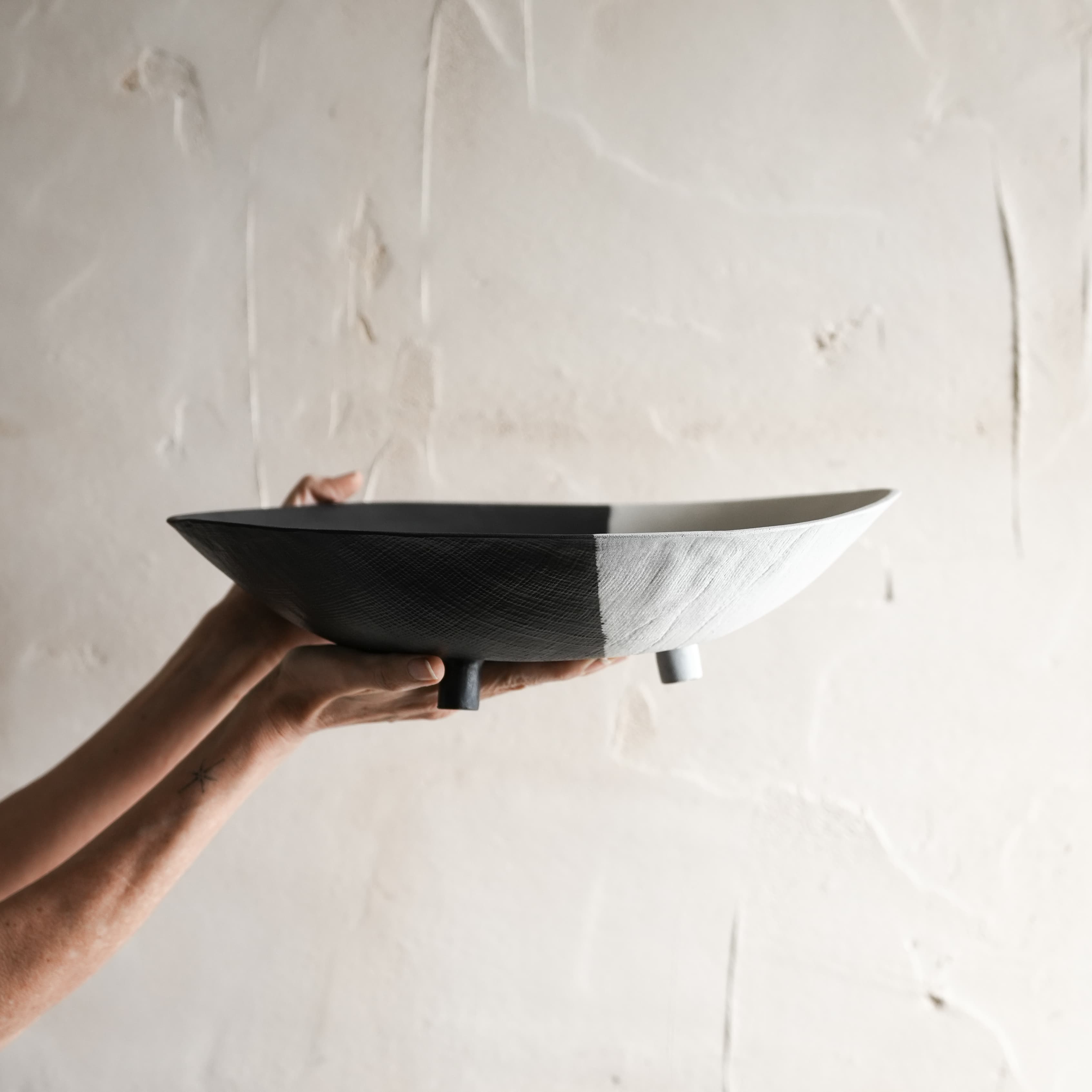 Person holding a black ceramic bowl against a light background