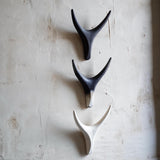 Side angel of three ceramic antlers wall sculptures in black, white, and painted finish arranged vertically