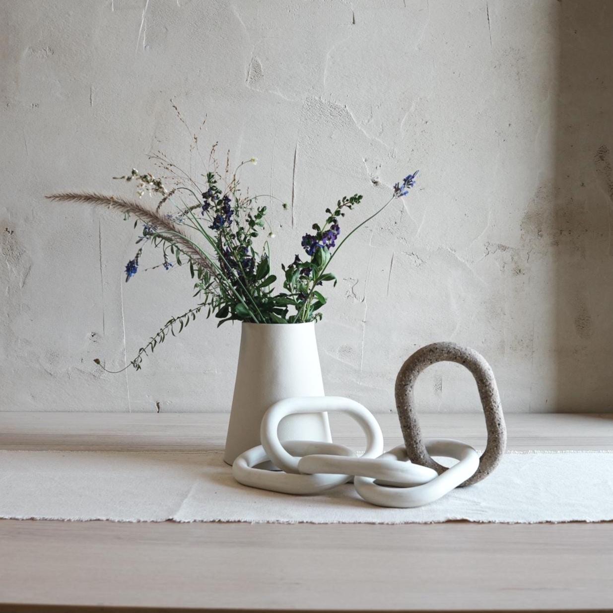 Minimalist porcelain chain sculpture styled with ceramic vase