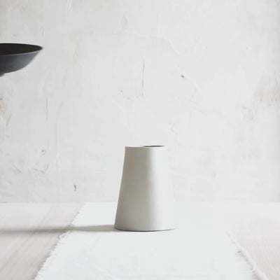 Video showing interchangeable ceramic bowls in black, white, and black and white finishes on a white stoneware pedestal vase. 