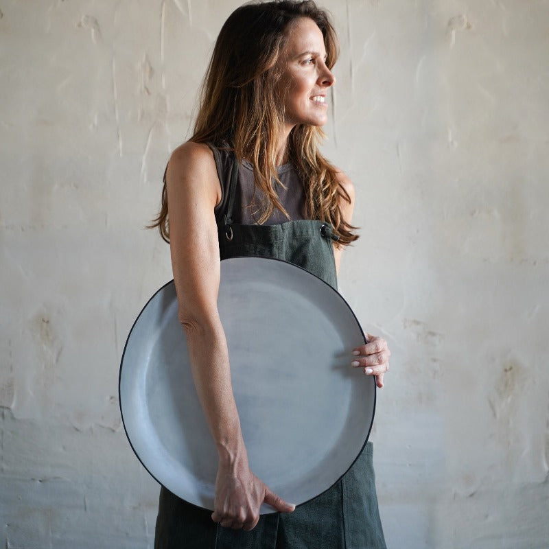 woman holds large white decorative platter on its side