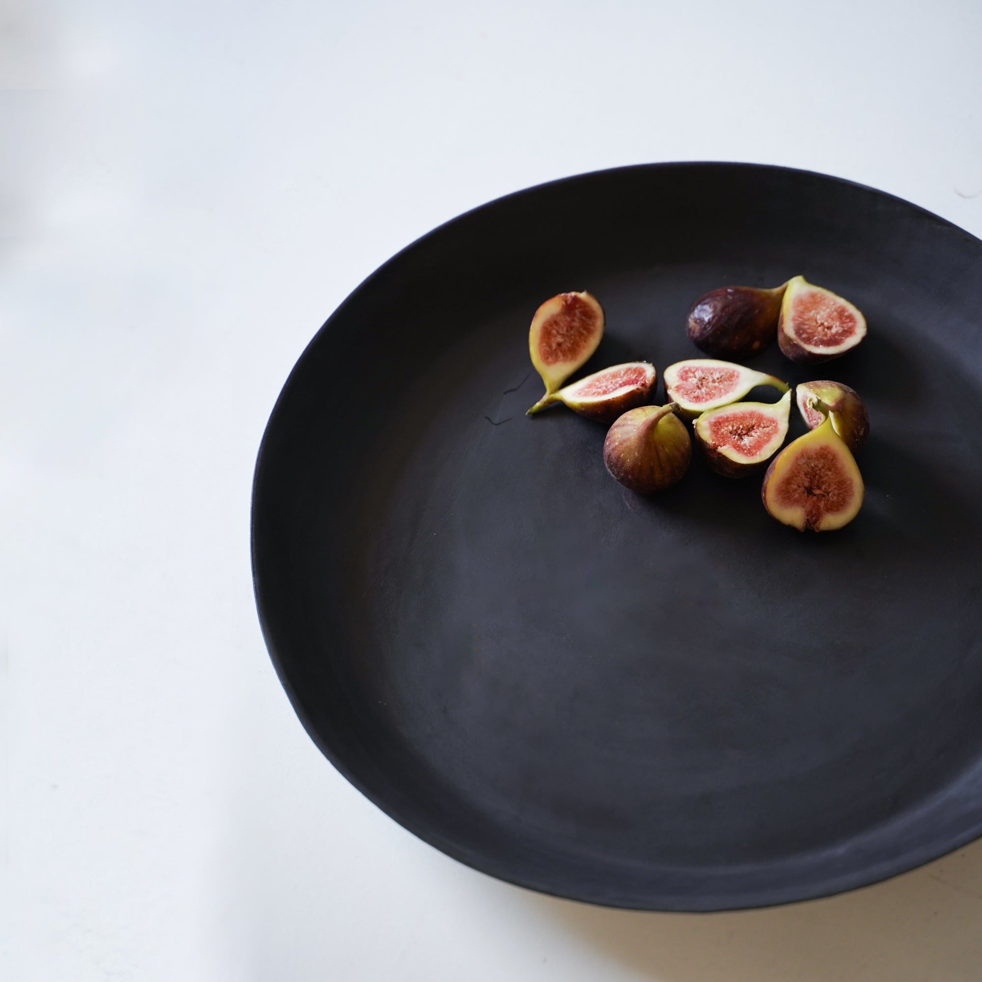 large black round tray with a few figs in the corner for size