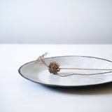 detail image of organic white and black stoneware rim, styled with flowers