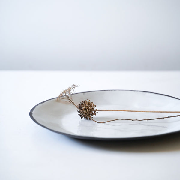 detail image of organic white and black stoneware rim, styled with flowers