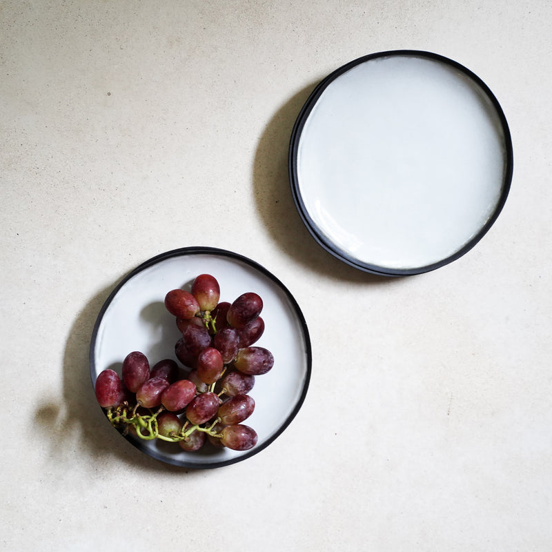 two black rimmed plates and grapes
