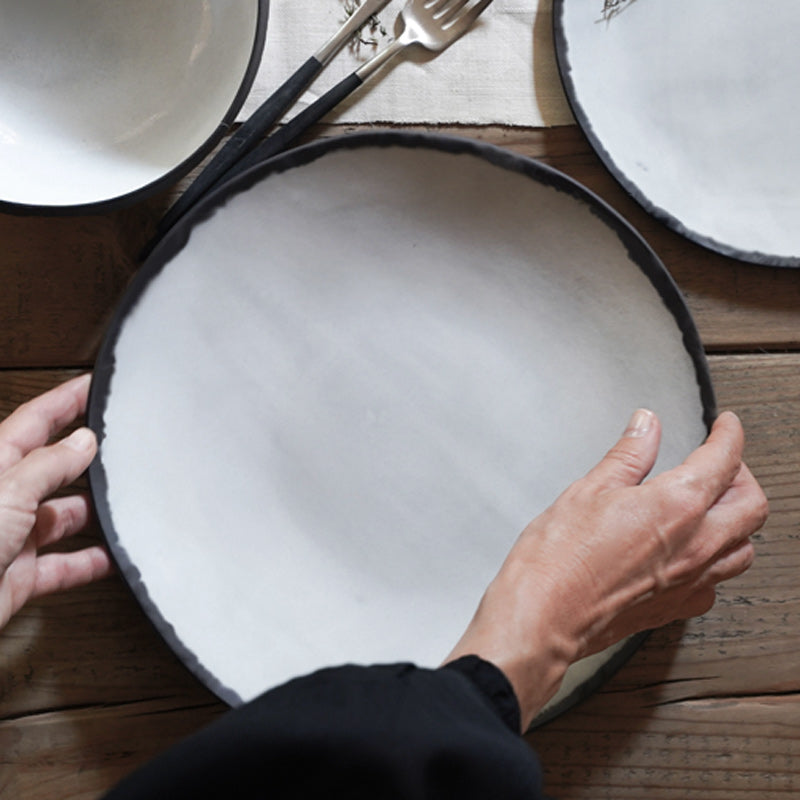 hand set white plate with black rim on table