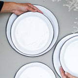 hand sets farmhouse salad plates onto farmhouse dinner plates