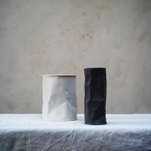 white crumpled vase next to black crumpled vase