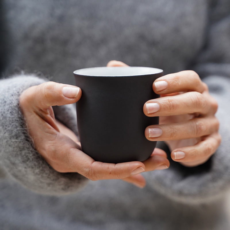 detail image of a woman holding a ceramic cup of coffee