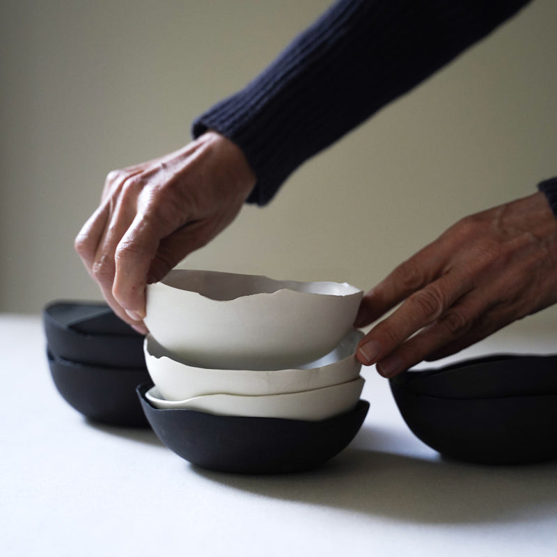 hands place a white unfinished bowl into a stack