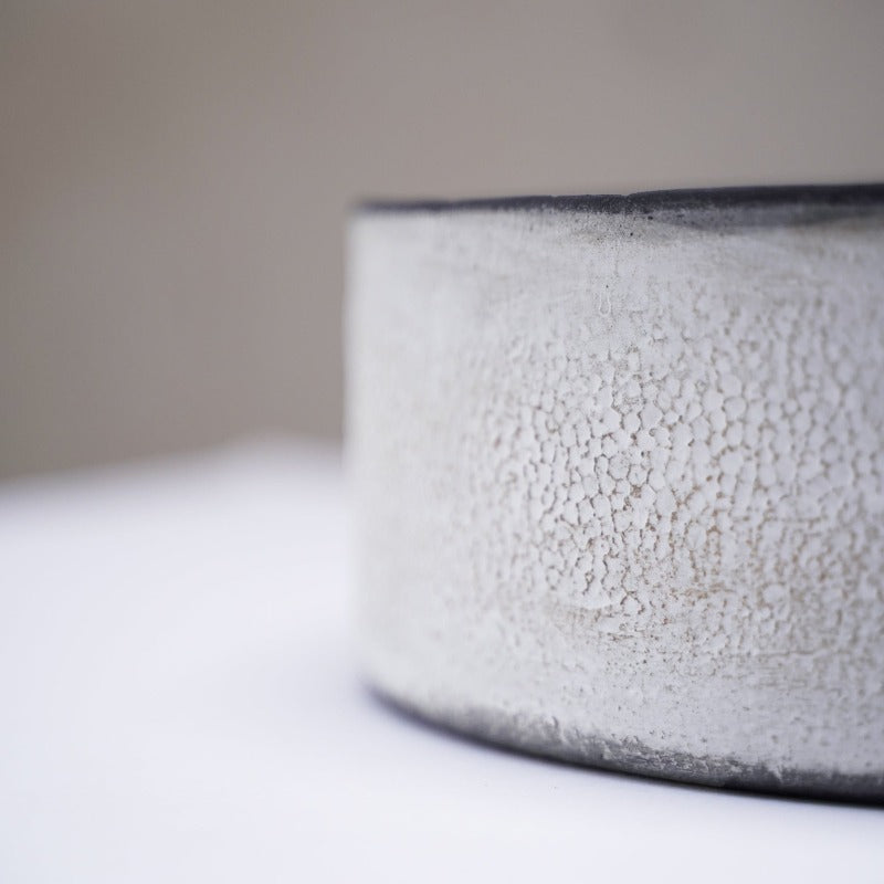 detail image of the special white texture on the exterior walls of a black, handmade ceramic cylinder bowl