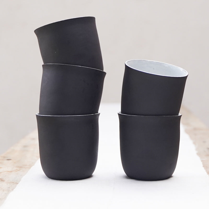 two stacks of black coffee cups. the exteriors are black and the interiors are white