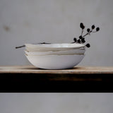 stack of unfinished white bowls with a black flower