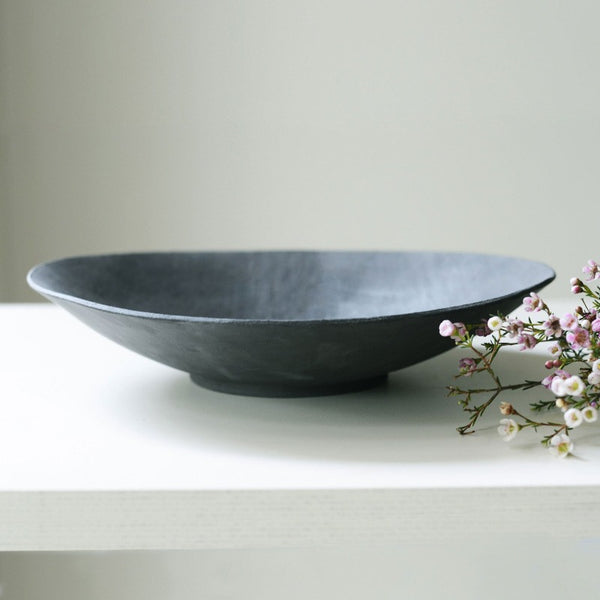 large black round bowl elegantly phtographed from an angle and presented with flowers