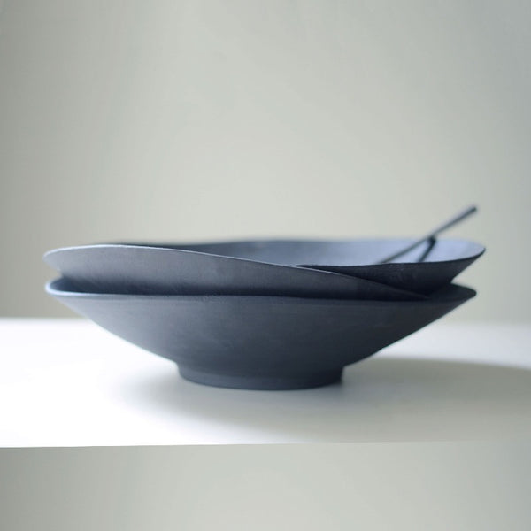 three artistically stacked black ceramic bowls photographed from the profile view
