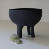 matte black bowl with four tall legs, styled with seashells