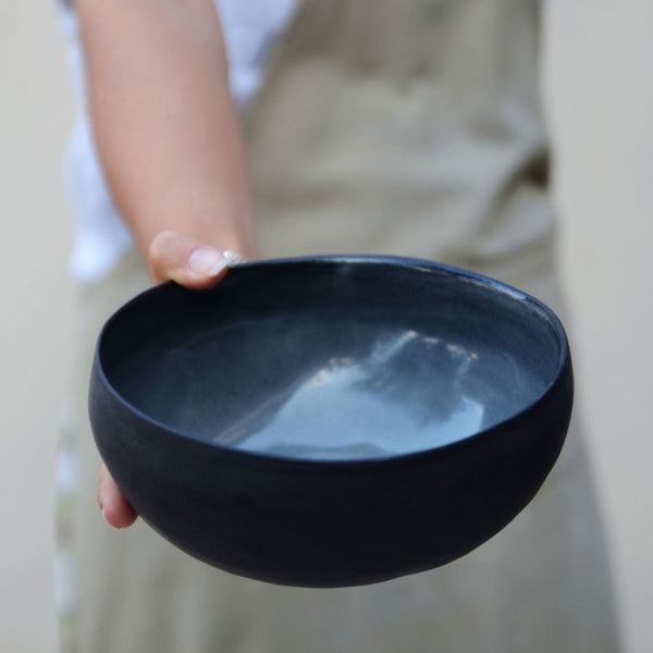 one hand holds empty black ramen bowl