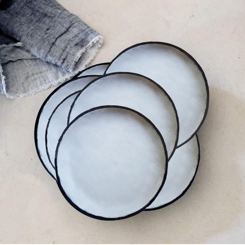 artistically placed white ceramic plates with black rims, photographed from the aerial position