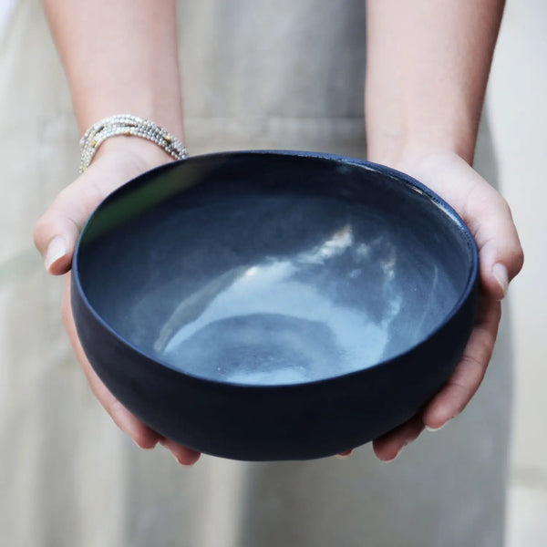 two hands holding a hand-made black soup bowl