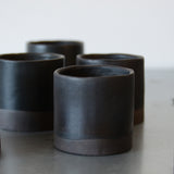 black double espresso cups. crafted from black stoneware and glazed black with an exposed base. photographed from a profile view
