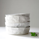 a stack  of white crumpled bowls