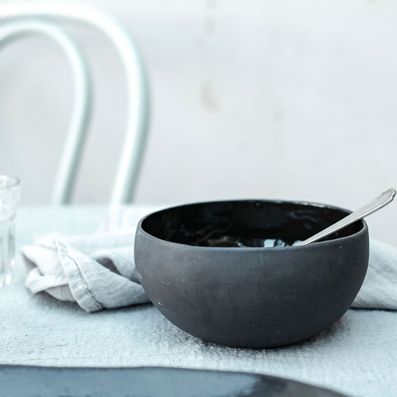 black coconut bowl on a table with a spoon